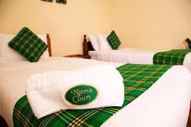 Twin beds dressed in green tartan with a Njema Court towel